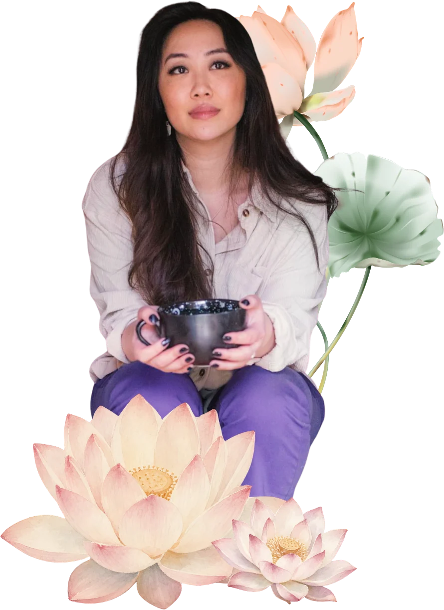 Michelle Saya seated with a dark ceramic cup, among lotus flowers